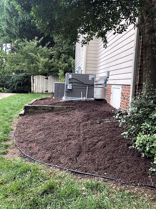 Fresh mulch bed around the AC unit with crisp edges after service