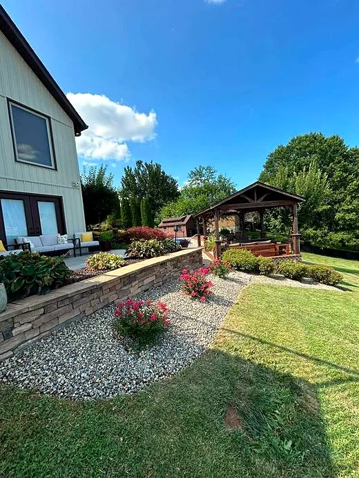 Backyard patio with a finished river rock bed and stone wall after service