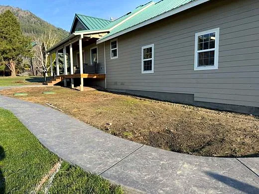 Bare dirt strip along a driveway before landscaping work